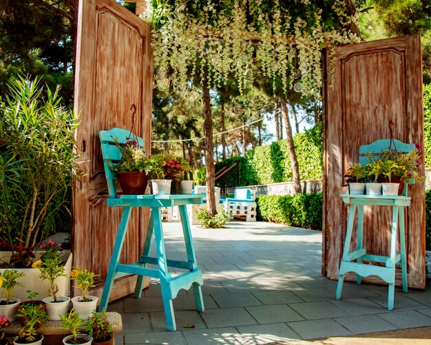 Ingang van het restaurant met houten deuren en twee turquoise stoelen met plant