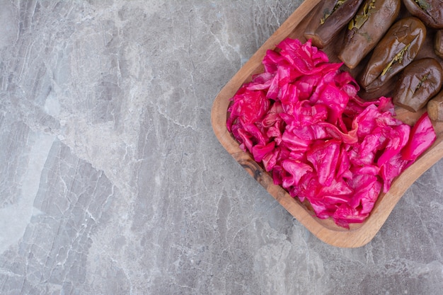 Ingelegde aubergines en rode kool op een houten bord.