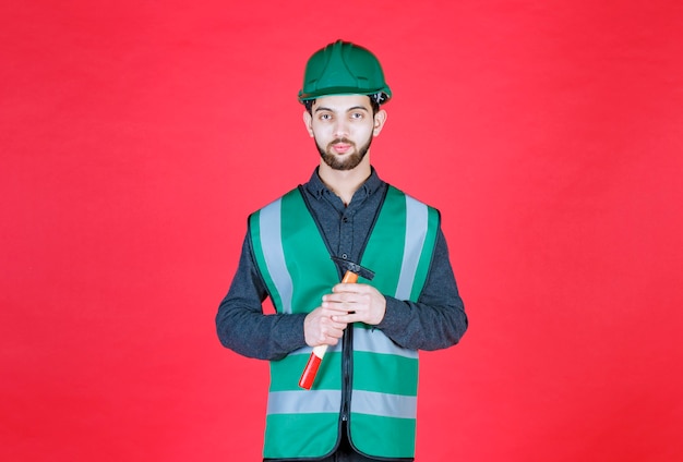Ingenieur in groen uniform en helm met een houten bijl.
