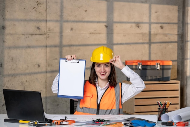 Ingenieur in helm en vest civiele werknemer slimme jonge brunette meisje erg enthousiast over project