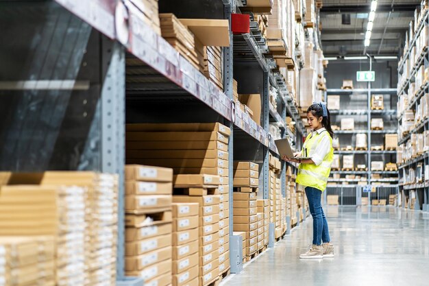 Ingenieursvrouw controleert voorraaddetails op tablet voor het controleren van dozen met logistiek in magazijn