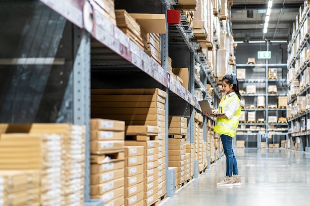 Ingenieursvrouw controleert voorraaddetails op tablet voor het controleren van dozen met logistiek in magazijn