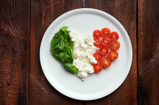 Ingrediënten voor caprese salade in de vorm van een hart. italiaanse vlag van traditionele voedingsmiddelen
