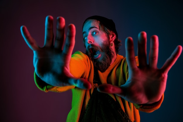 Inlijsten, selfie. Kaukasisch man's portret op de achtergrond van de gradiëntstudio in neonlicht. Mooi mannelijk model met hipsterstijl. Concept van menselijke emoties, gezichtsuitdrukking, verkoop, advertentie.