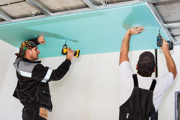 Installateurs van gipsplaten. Mannen die een vals plafond van gipsplaten monteren.Eenvoudige en betaalbare renovatie van gebouwen