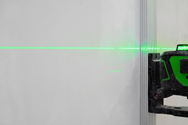 Gratis foto installatie van nieuwe tegels op de muur met behulp van een laserniveau laserniveau verlicht de professionele benadering van de installatieplaats