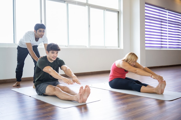 Instructeur helpt beginners om voorwaartse buiging te doen