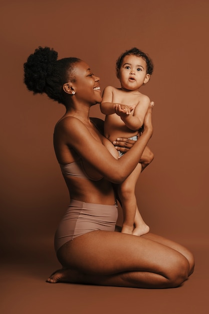 Gratis foto intiem portret van mooie moeder die haar jonge kind vasthoudt