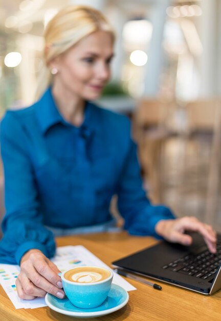 Intreepupil oudere zakenvrouw die op laptop werkt en koffie heeft