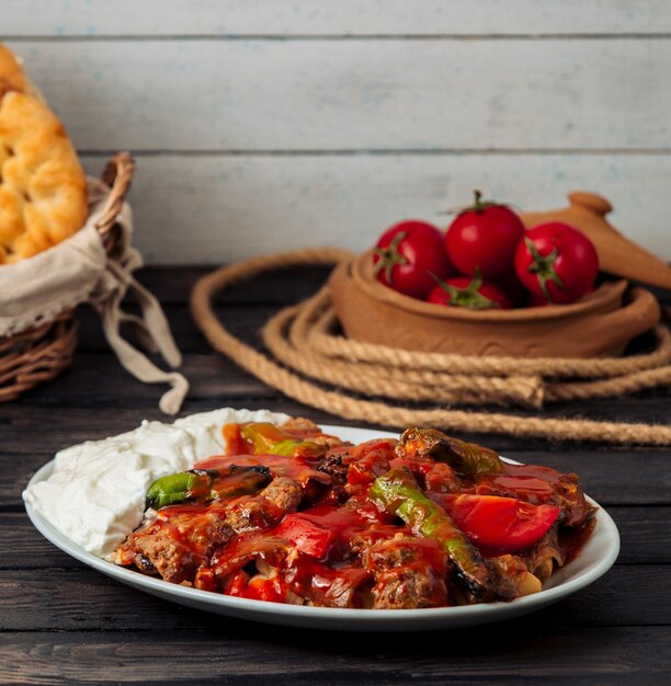 Iskender kebab gegarneerd met tomatensaus, geserveerd met yoghurt