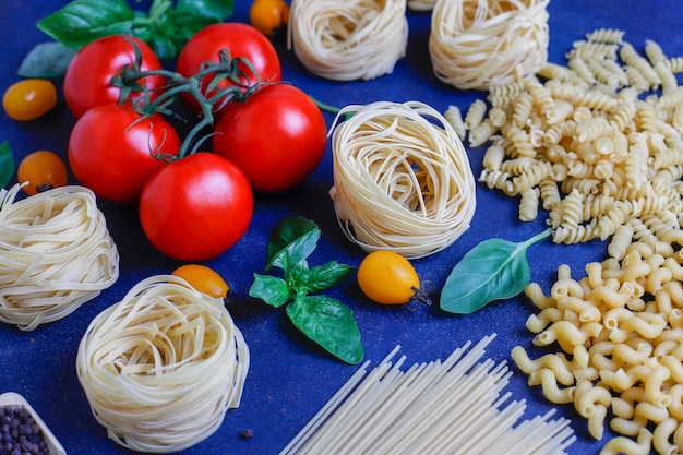 Italiaans eten . Italiaanse keuken. Ingrediënten tomaten, gele kerstomaten, verse basilicum, zwarte peperkorrels, verschillende pasta.