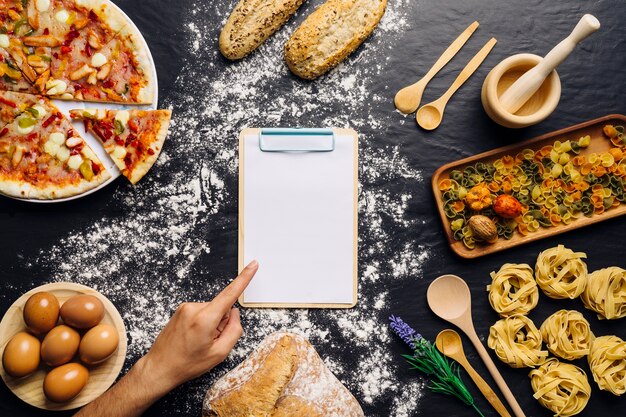 Italiaanse eten decoratie met vinger wijst op klembord