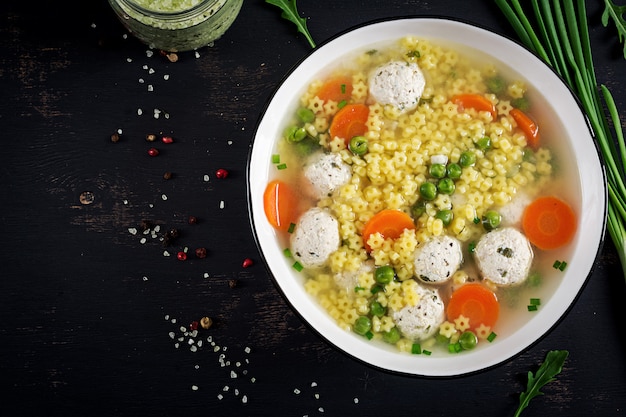 Gratis foto italiaanse vleesballensoep en stelline-gluten vrije deegwaren in kom op zwarte lijst.