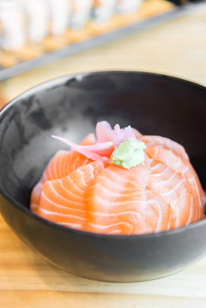 Japanse rijst met zalmsashimi bovenop in zwarte kom