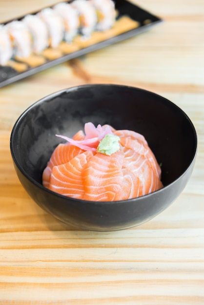 Japanse rijst met zalmsashimi bovenop in zwarte kom