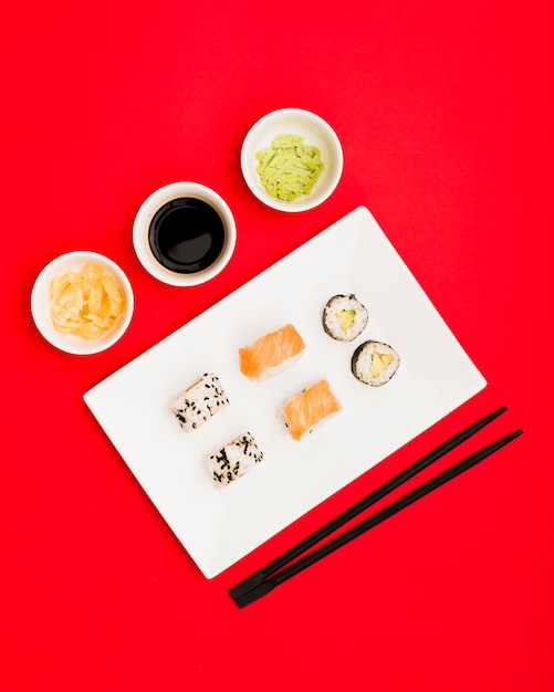 Japanse sushi met sojasaus; gember en wasabi over rode achtergrond