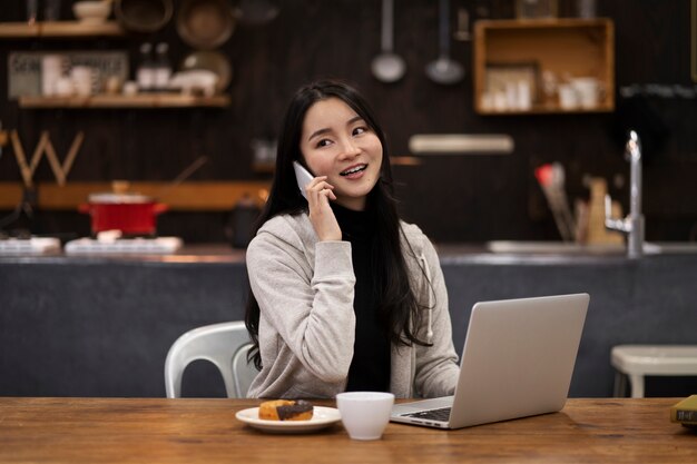 Japanse vrouw praat op haar smartphone terwijl ze in een restaurant werkt