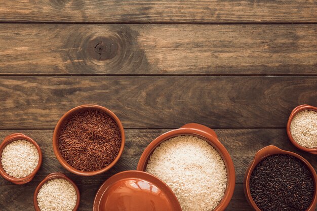 Jasmijnbruine volkoren rijst; witte rijst en biologische rijst in kom op houten tafel
