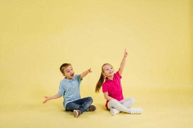 Jeugd en droom over grote en beroemde toekomst Mooie kleine kinderen geïsoleerd op gele studioachtergrond