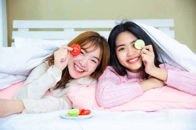 jeugdvrienden liggen onder deken met kussens op bed