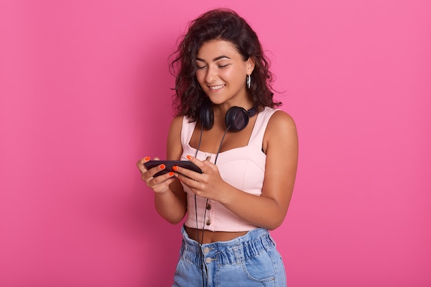 Jong aantrekkelijk krullend haired meisje status, die hoofdtelefoons hebben rond hals