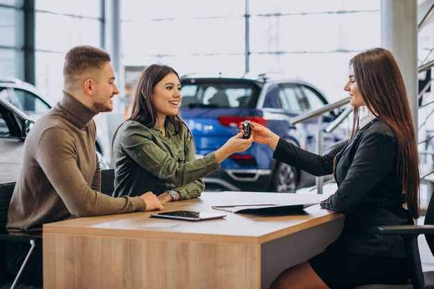 Jong echtpaar praat met een verkoper in een autosalon