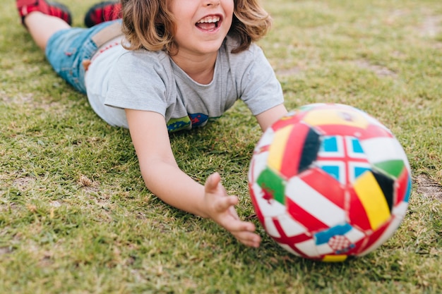 Gratis foto jong geitje dat in gras ligt en met bal speelt