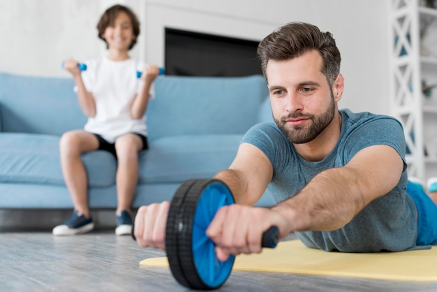 Gratis foto jong geitje en zijn vader die sport thuis doen