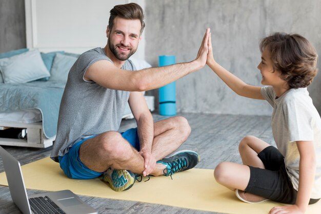 Jong geitje en zijn vader die sport thuis doen