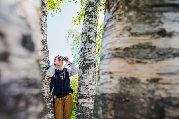 Gratis foto jong geitje met zijn verrekijker in het park