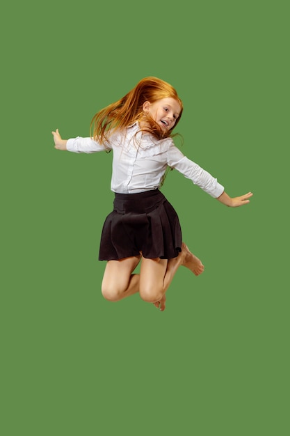 Jong gelukkig Kaukasisch tienermeisje springen in de lucht, geïsoleerd op groen. Mooi vrouwelijk portret van halve lengte
