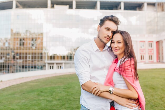 Jong getrouwd stel poseren samen voor modern gebouw tijdens gezamenlijk weekend