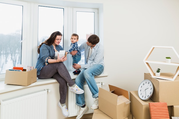 Jong gezin ontspannen in hun nieuwe huis met bewegende kartonnen dozen