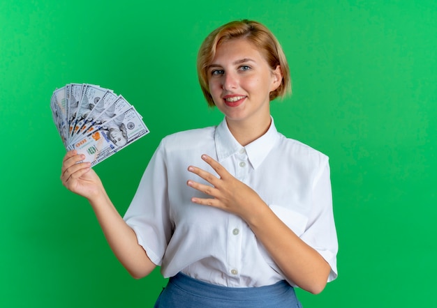 Gratis foto jong glimlachend blond russisch meisje houdt geld en gebaren vier met vingers