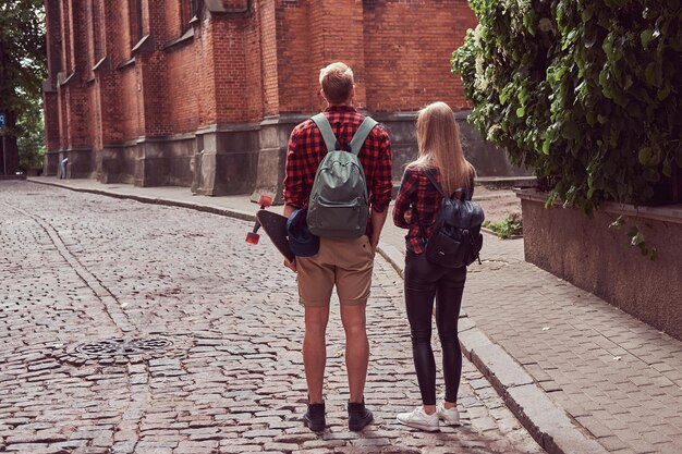 Jong hipsterpaar, knappe skater en zijn vriendin wandelen door de oude straten van Europa.