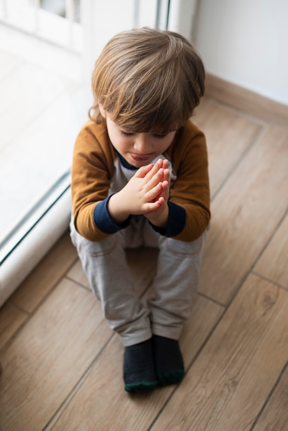 Gratis foto jong kind dat een gebed thuis zegt