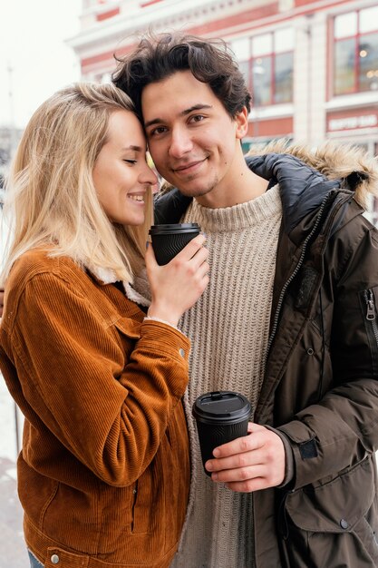 Jong koppel buiten genieten van kopje koffie