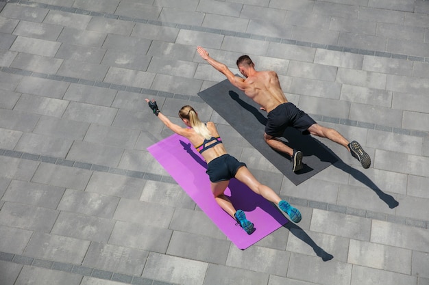 Jong koppel in sportoutfit die ochtendtraining buitenshuis doet, gezonde levensstijl