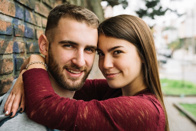 Gratis foto jong koppel knuffelen voor bakstenen muur