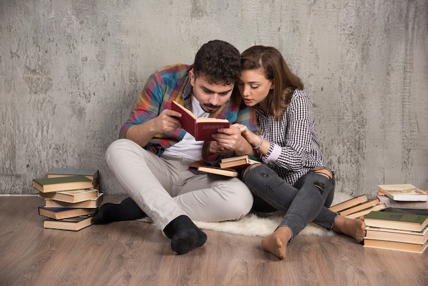 Jong koppel lezen van een interessant boek zittend op de vloer