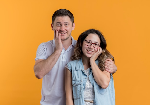 Jong koppel man en vrouw in casual kleding gelukkig en positief lachend over oranje