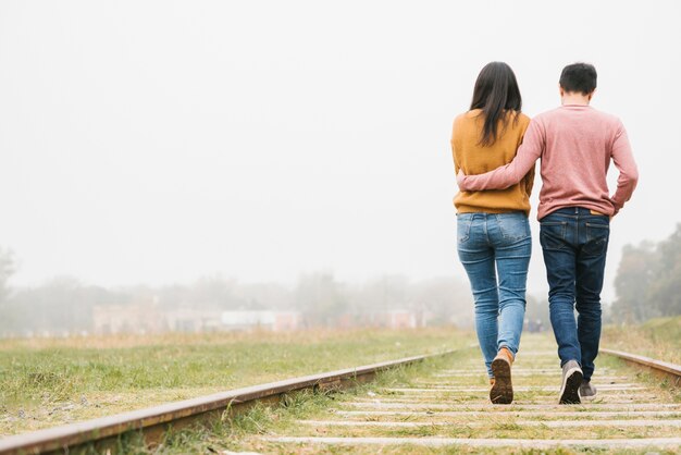 Jong koppel omarmen wandelen langs de sporen