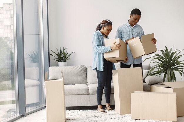 Jong koppel samen verhuizen naar nieuw huis. Afrikaans Amerikaans echtpaar met kartonnen dozen.