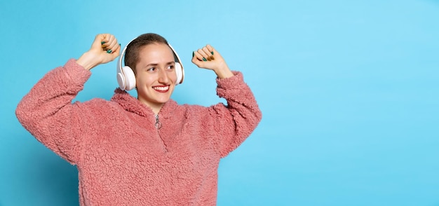 Jong lachend meisje luisteren naar muziek in koptelefoon geïsoleerd op blauwe achtergrond Flyer