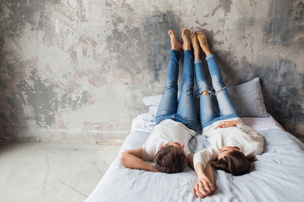 Jong lachend paar liggend op bed thuis in casual outfit