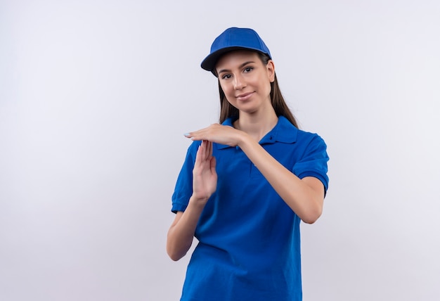 Jong levering meisje in blauw uniform en pet camera kijken time-out gebaar met handen kijken