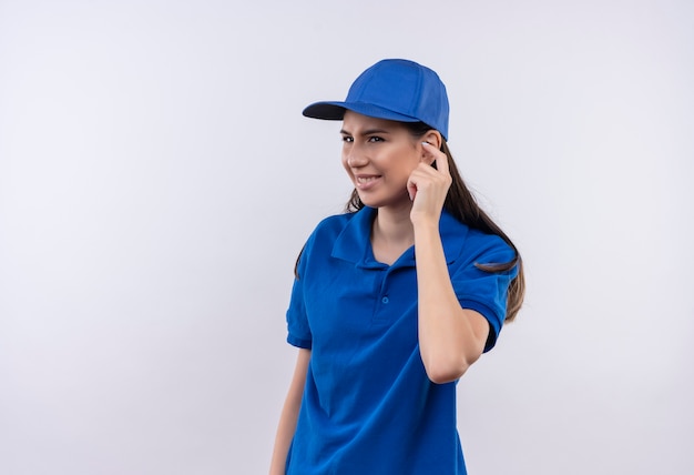 Jong leveringsmeisje in blauw uniform en GLB sluitend oor met vinger met geïrriteerde uitdrukking