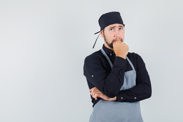 Jong mannetje dat in overhemd, schort omhoog kijkt en peinzend, vooraanzicht kijkt.