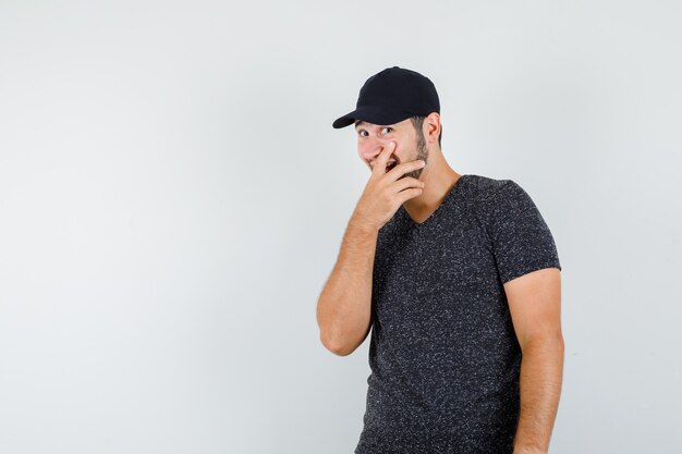 Jong mannetje dat in t-shirt en pet glimlacht en verrast kijkt