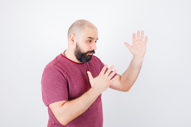 Jong mannetje dat karatekarbonade in roze t-shirt toont en flexibel kijkt. .